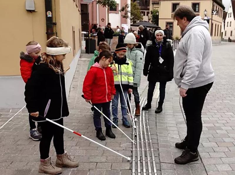 Grundschuldkinder erkunden das Blindenleitsystem mit Blindenstöcken